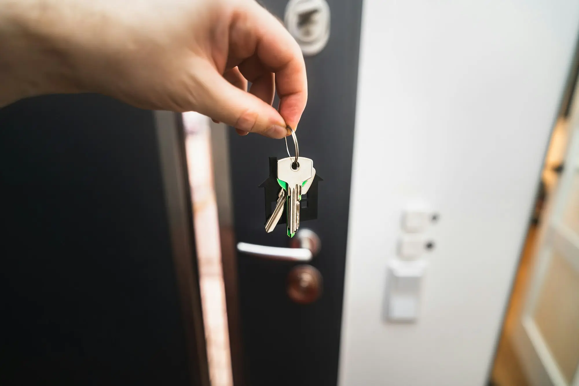 Hand holding house keys at the front door